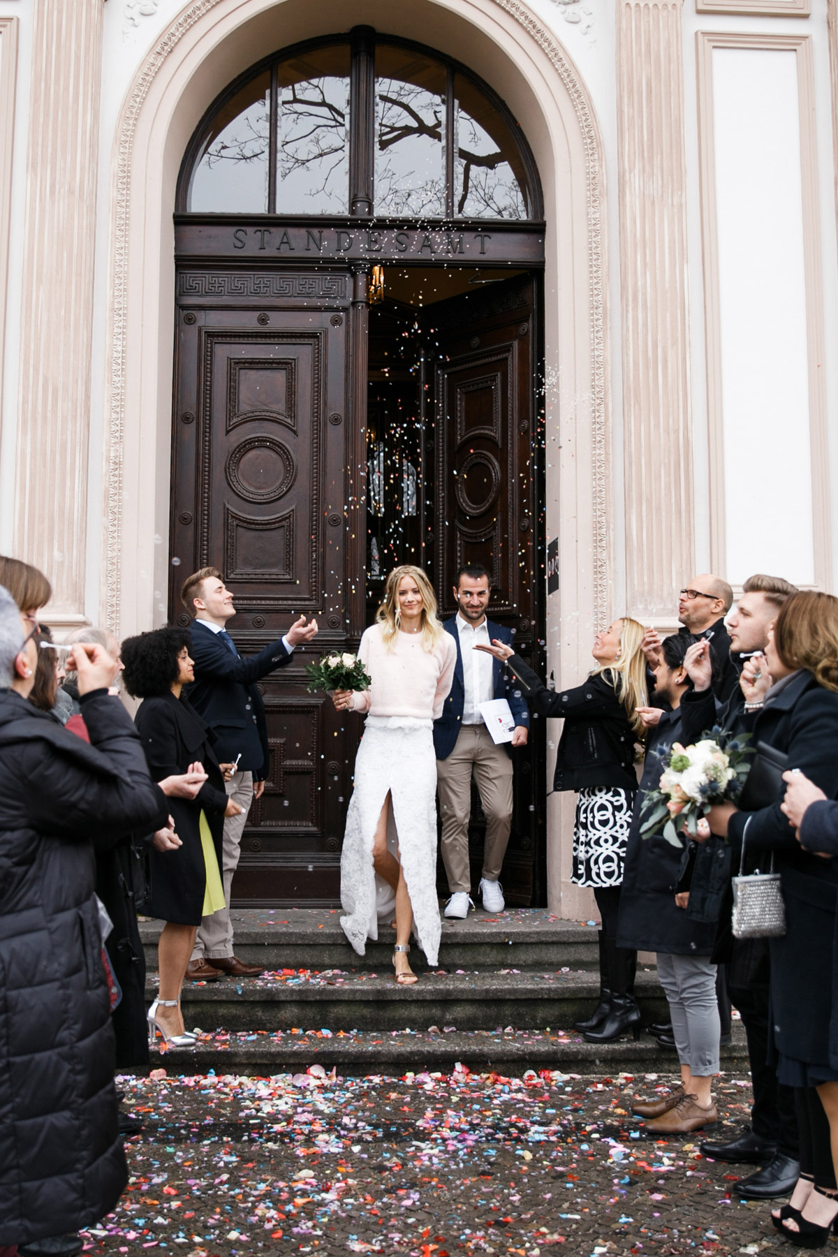 Villa Kogge Hochzeit: Brautpaar verlässt die Villa durch die große Holztür und wird von den Gästen mit Konfetti bejubelt