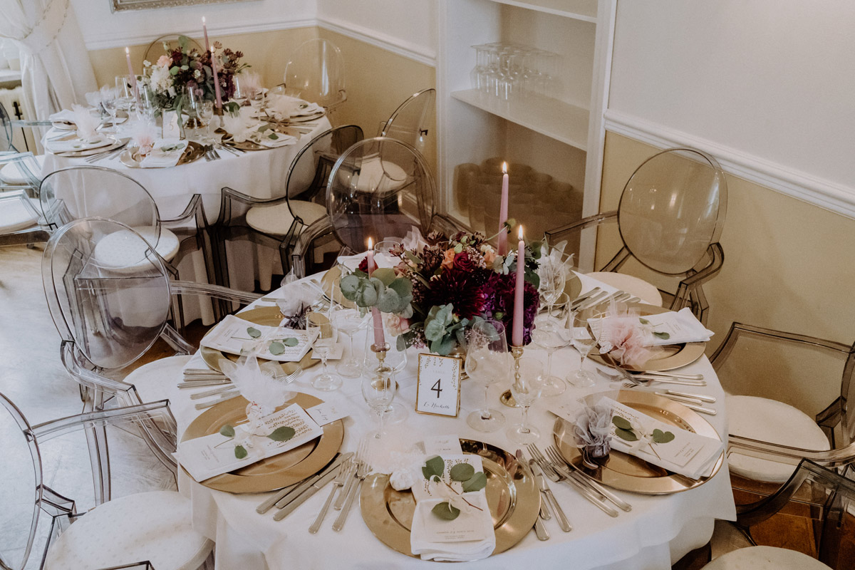 Hochzeitslocation bei Potsdam: Festlich dekorierter Gut Schloss Golm Raum mit prunkvollem Kronleuchter und modernen Acrylstühlen