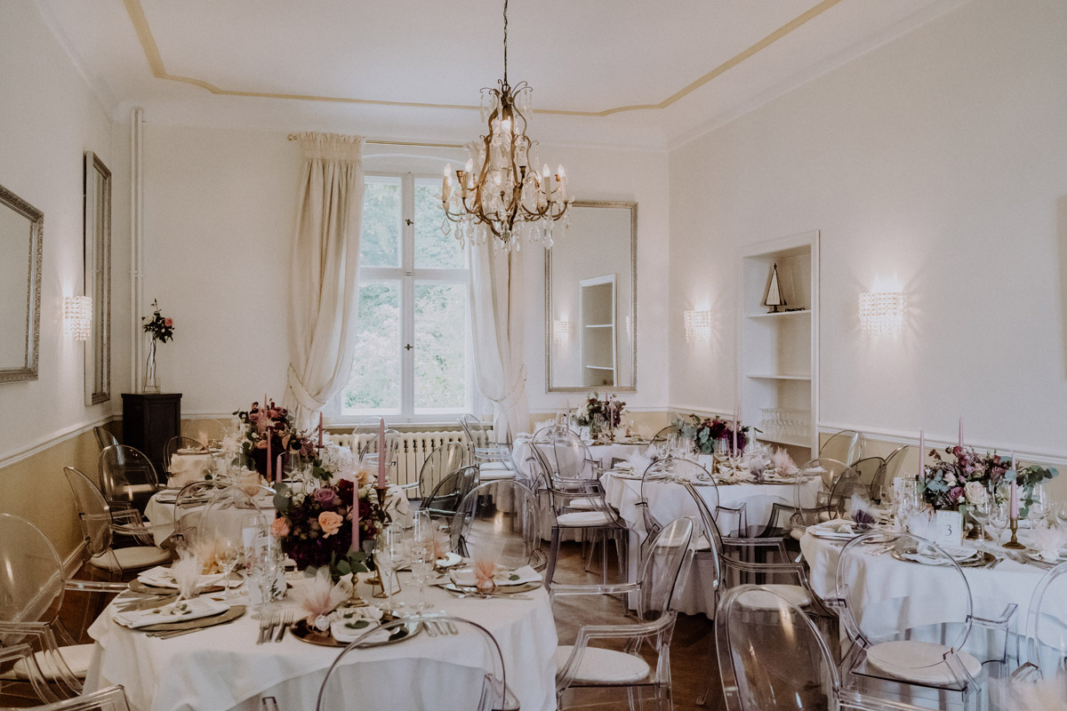 Festsaal von Gut Schloss Golm: Elegante Tischdekoration für die Hochzeitsfeier: Goldene Platzteller und rosa Kerzen