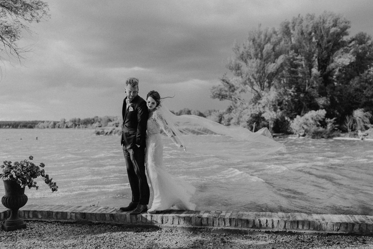 Gut Schloss Golm Hochzeit: Brautpaar-Portrait vor dramatischer Wetter- und Wolkenkulisse direkt am Ufer des Zernsees