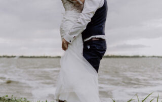 Hochzeitsfotograf Potsdam: Emotionales Hochzeitsfoto auf Gut Schloss Golm, Bräutigam hebt seine lachende Braut am stürmischen Zernsee vor Freude hoch
