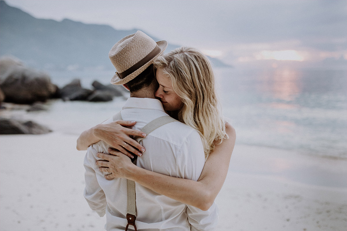 Hochzeitsfotograf Elopement: Nach der standesamtlichen Trauung in Berlin umarmt sich das Brautpaar nun glücklich bei Sonnenuntergang am Strand der Seychellen