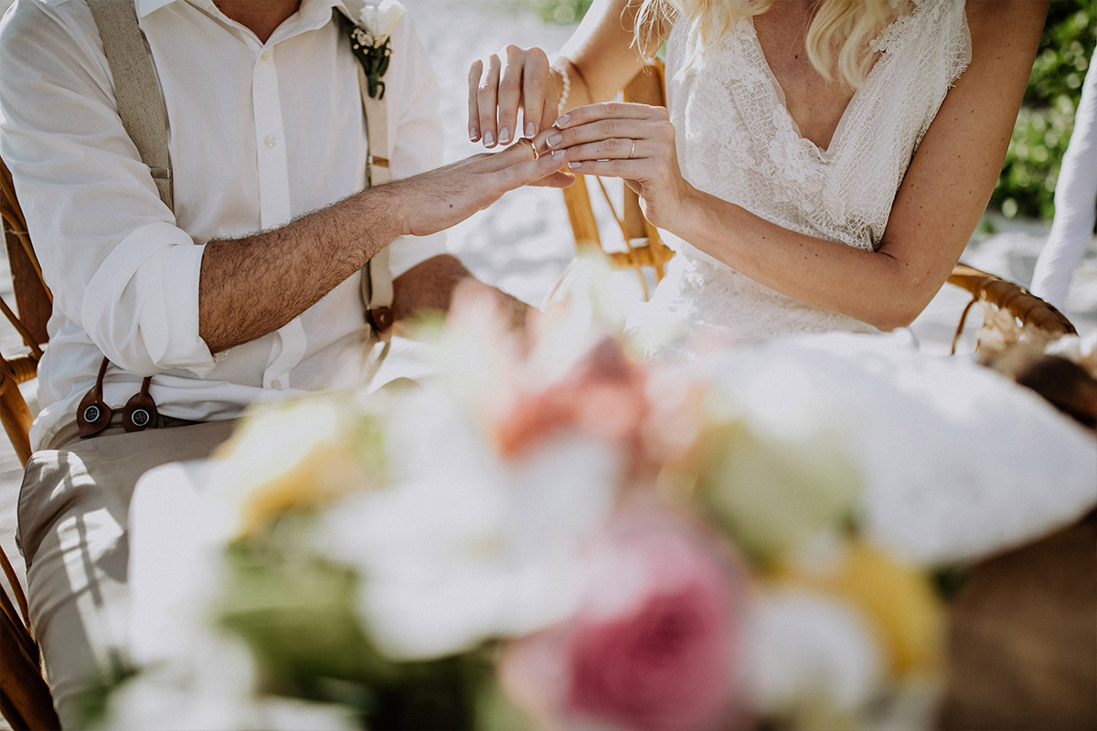 Hochzeitsfotograf Seychellen: Detailaufnahme des Ringtauschs bei der maritimen Hochzeitszeremonie am weißen Sandstrand, fernab vom Berliner Trubel