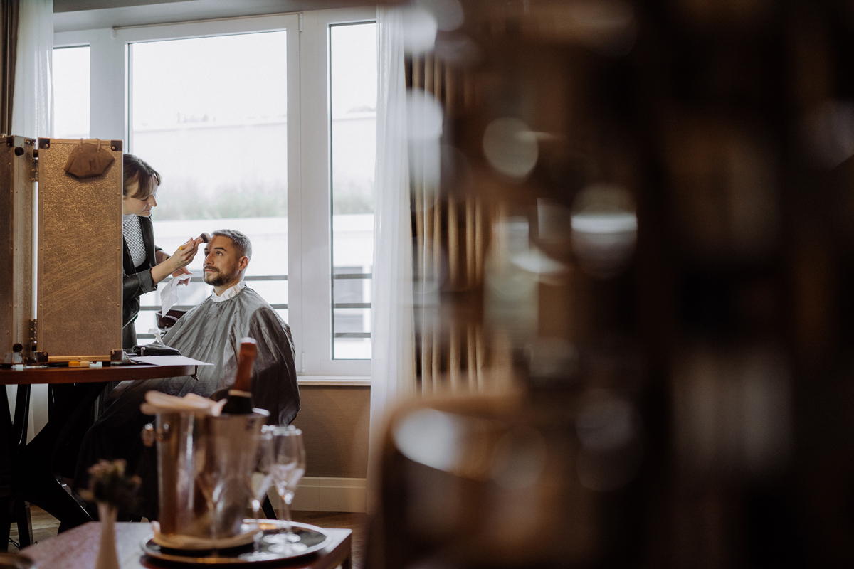 Bräutigam wird vor dem Spiegel frisiert