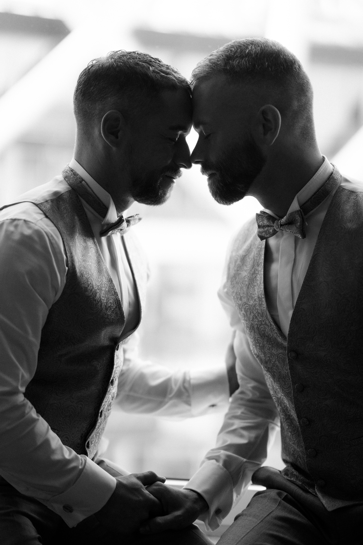 Künstlerische Hochzeitsfotografie in Schwarz-Weiß: Silhouette des Gay Wedding Paares im Gegenlicht beim Getting Ready im Ritz Carlton Hotel Berlin