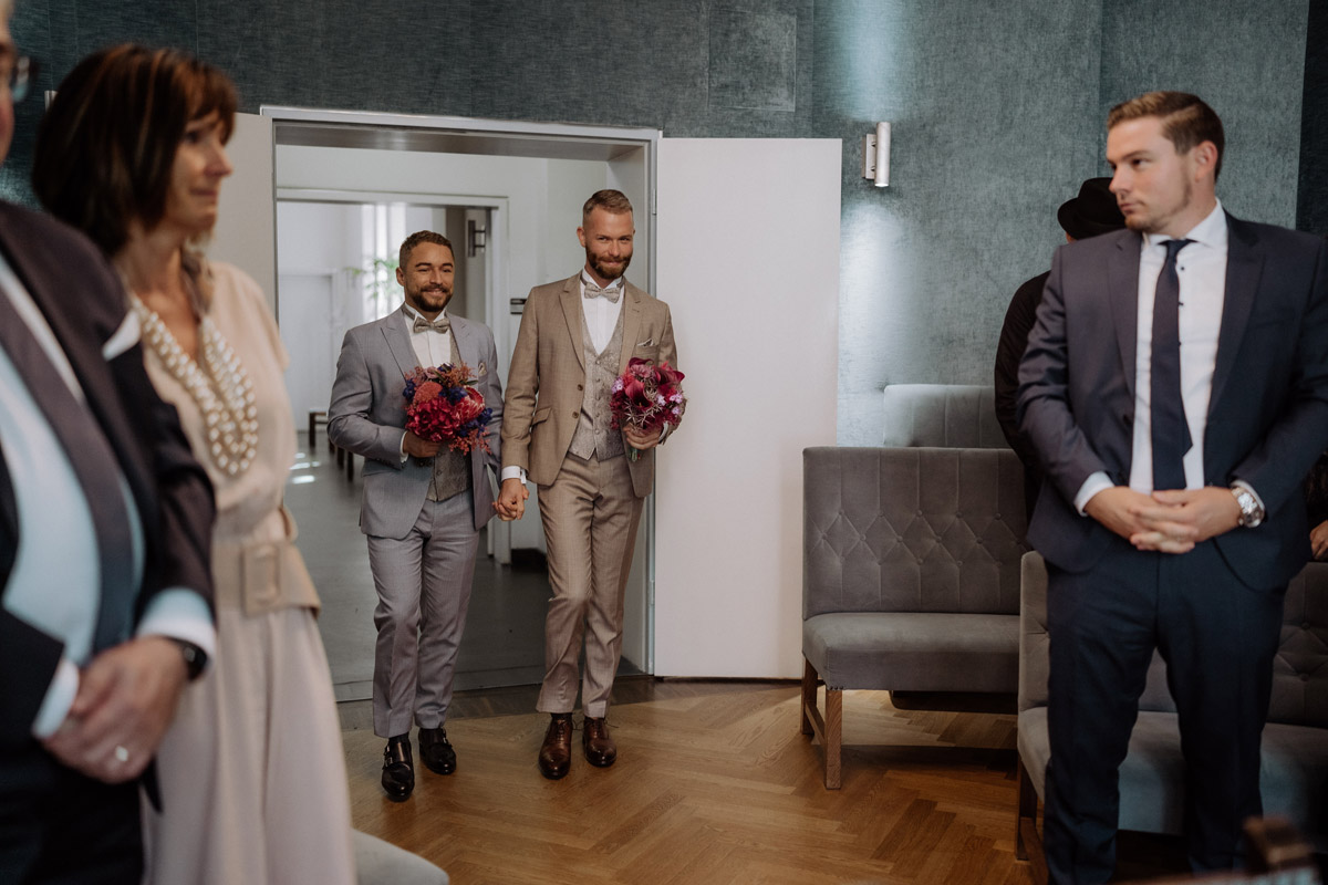 Bräutigame ziehen Hand in Hand in den Trauraum des Standesamt Potsdam ein