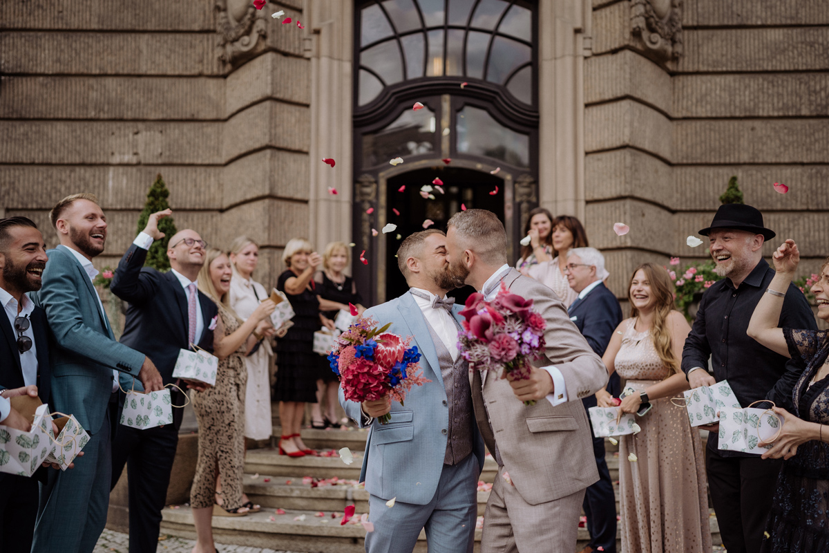 Romantischer Kuss im Blütenregen vor dem Rathaus: Emotionaler Moment für den Hochzeitsfotograf Potsdam