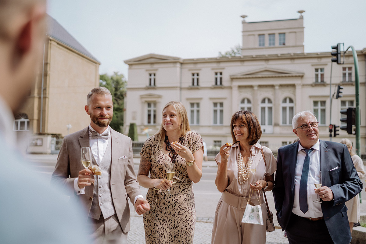 Gäste stehen vor dem Standesamt und stoßen mit Sekt an