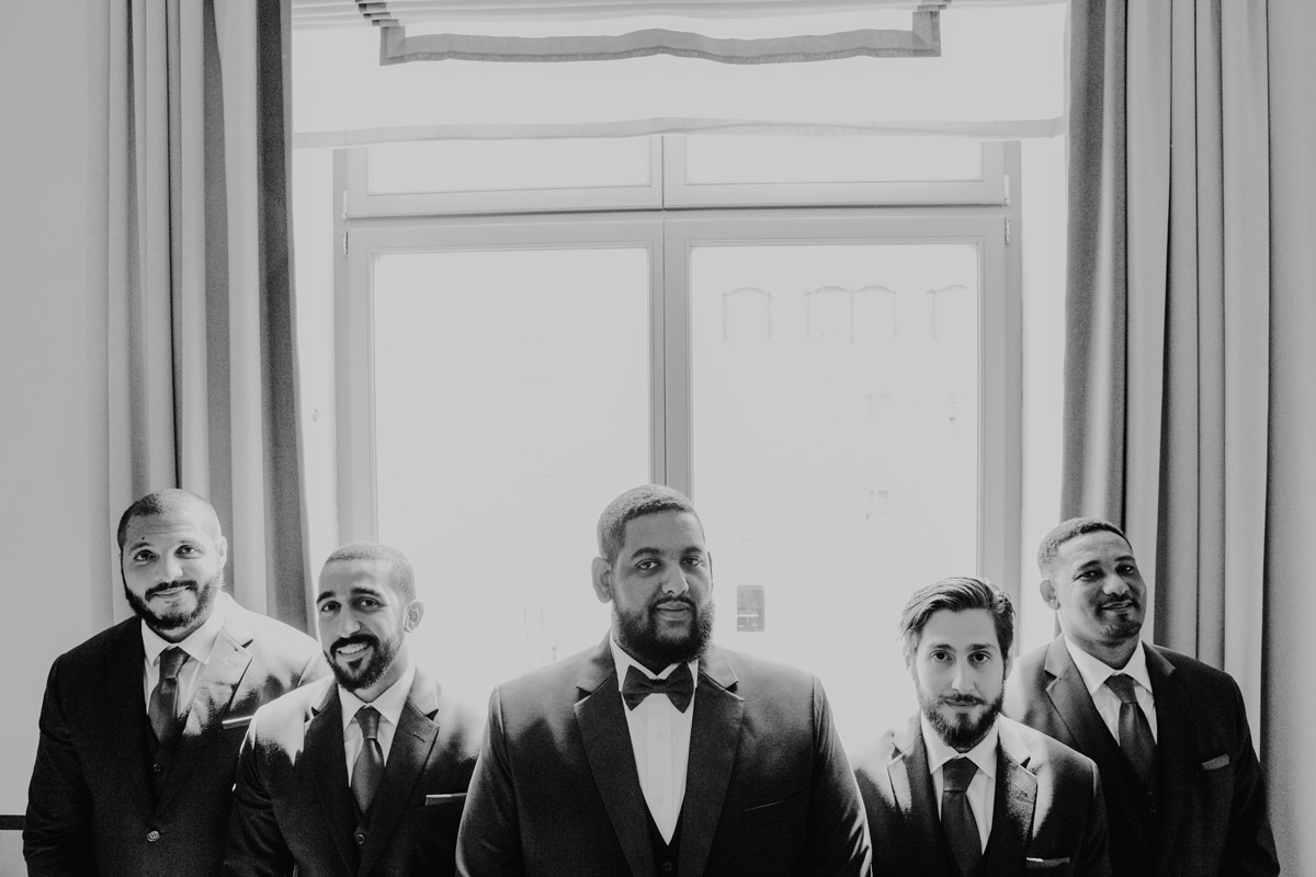 Klassisches Gruppenfoto der Groomsmen: Bräutigam mit seinen Best Men in Anzügen vor dem Fenster – Stilvolle Männerportraits zur Hochzeit