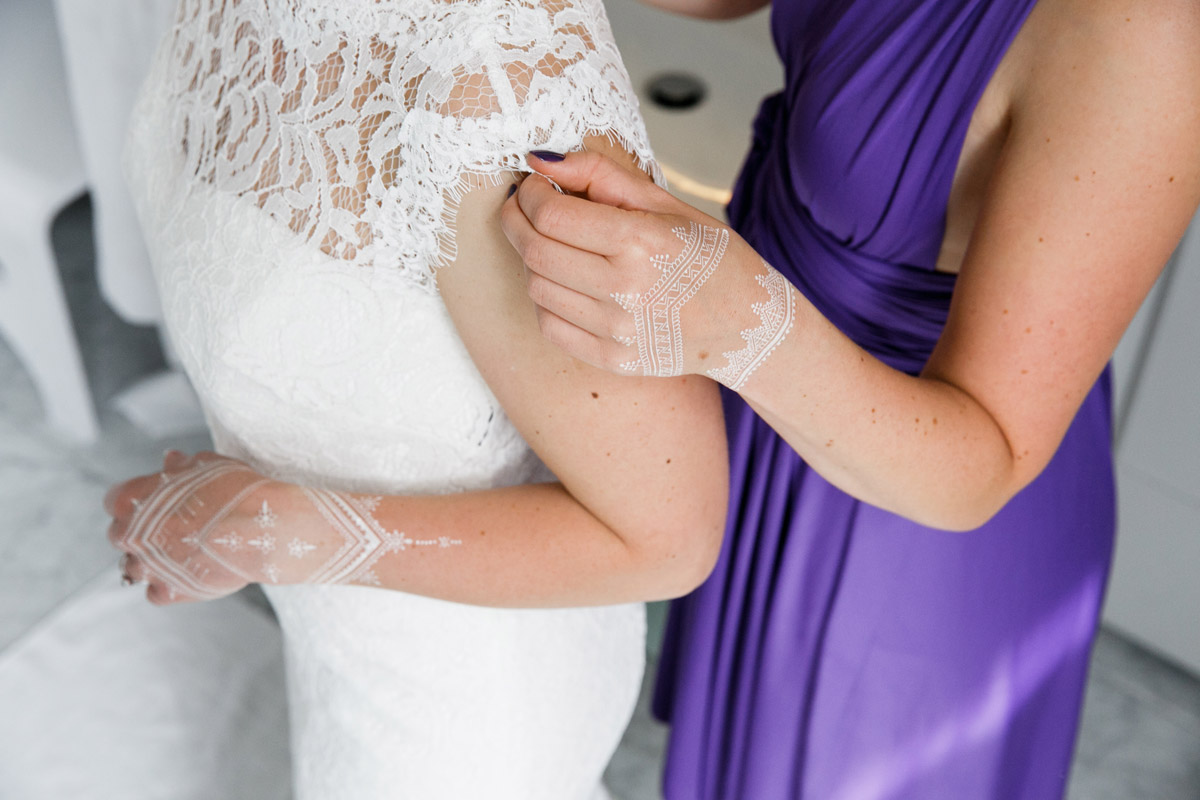 Brautjungfer hilft Braut in Kleid aus Spitze