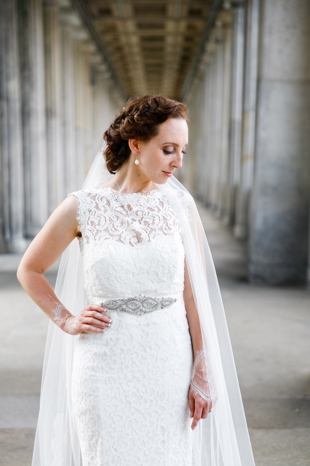Elegantes Brautportrait im Säulengang auf der Museumsinsel: Braut im Spitzenkleid mit Schleier vor den historischen Kolonnaden in Berlin Mitte