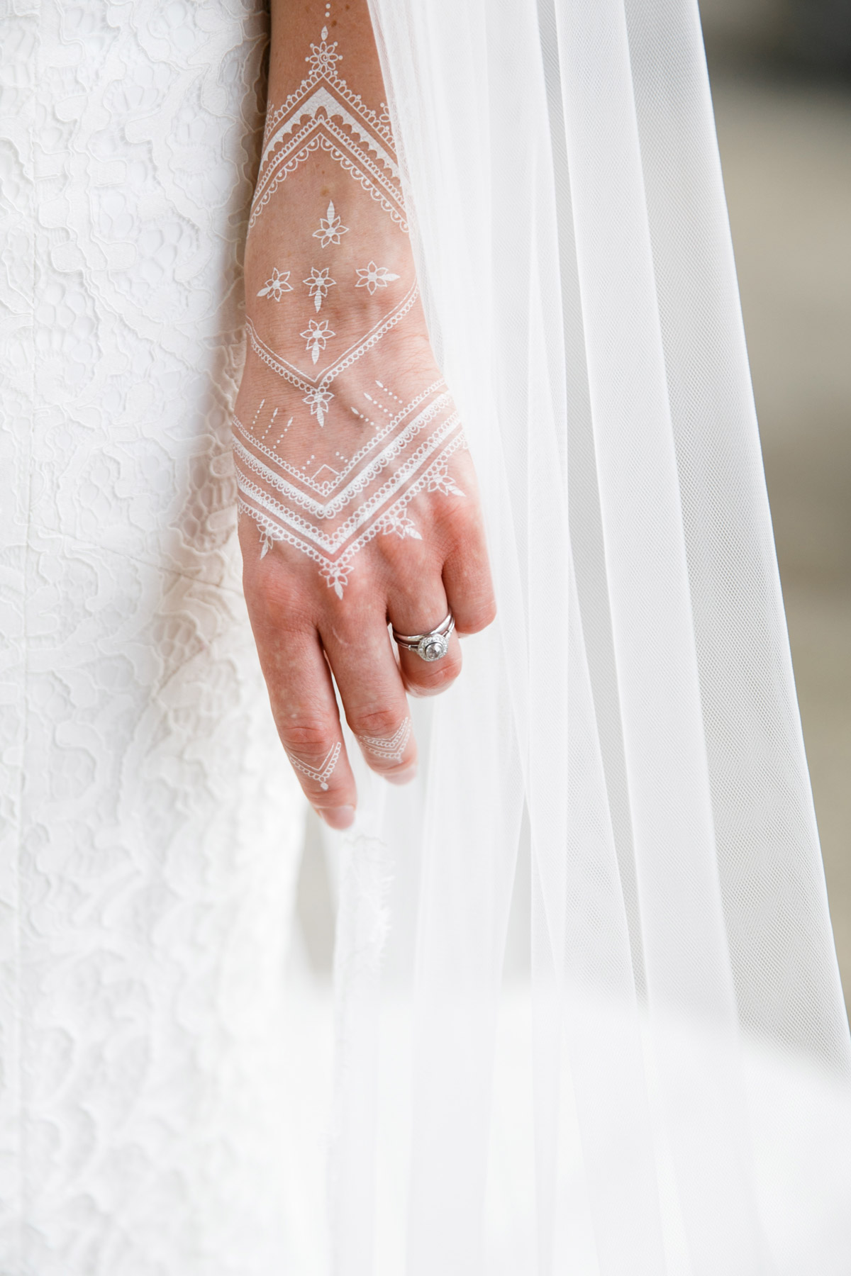Filigranes weißes Henna-Tattoo auf der Hand der Braut: Besonderes Detail einer multikulturellen Hochzeit, Fokus auf dem Verlobungsring
