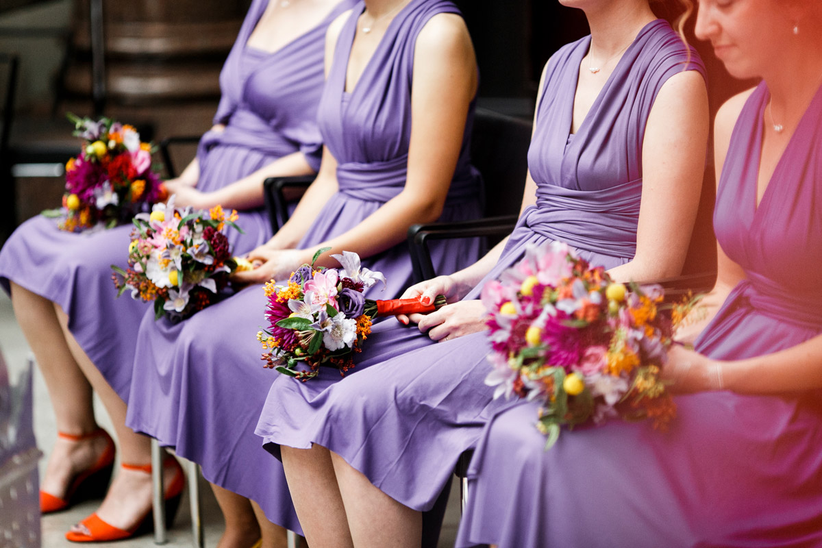 Sträuße liegen auf Schößen der vier Brautjungfern in lila Kleidern