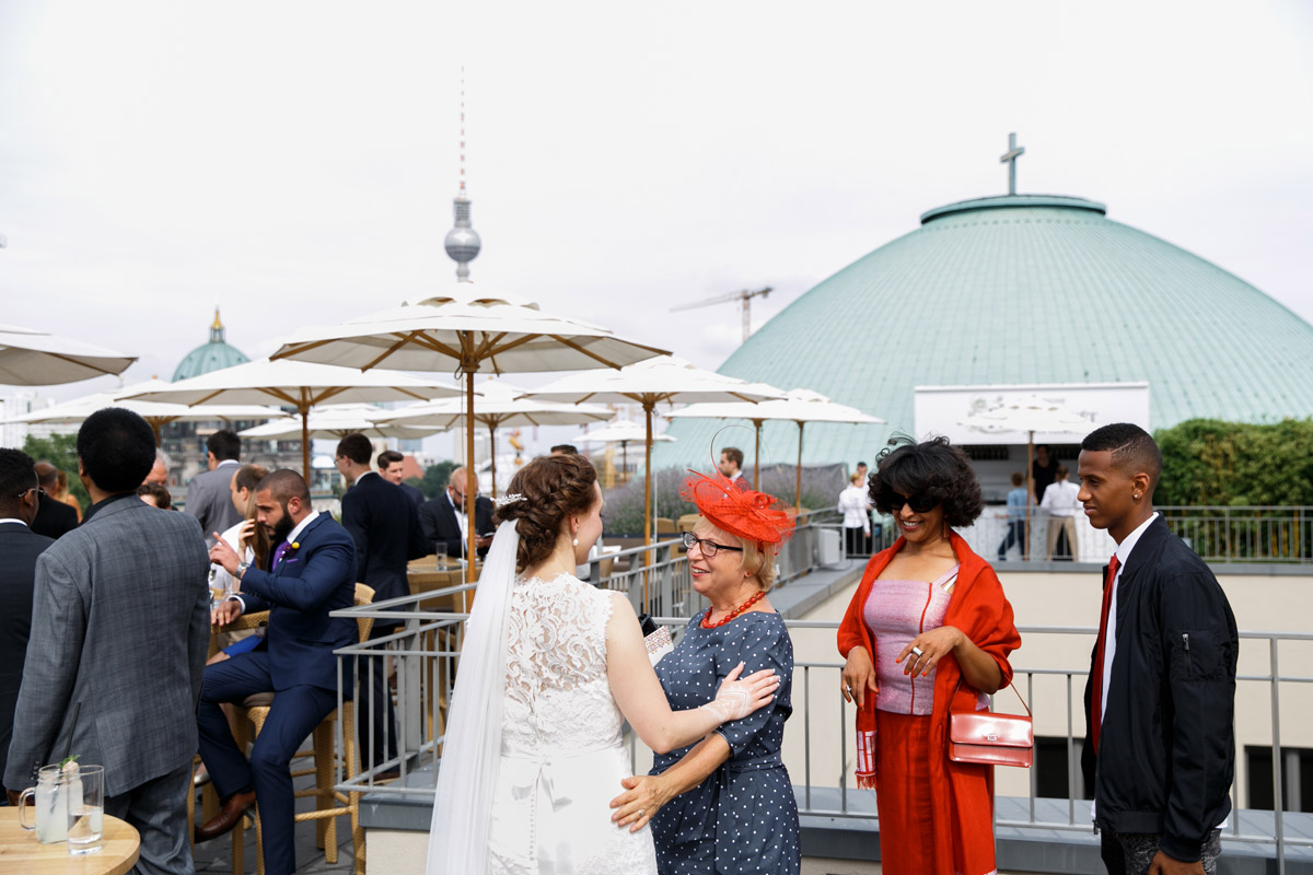 Internationale Gäste in traditioneller Kleidung und Abendgarderobe beim Empfang auf der Dachterrasse mit Blick auf den Berliner Dom