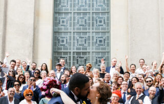 Großes Gruppenfoto Hochzeit Hotel de Rome Berlin: Brautpaar und 100 internationale Gäste jubeln auf der Treppe am Bebelplatz