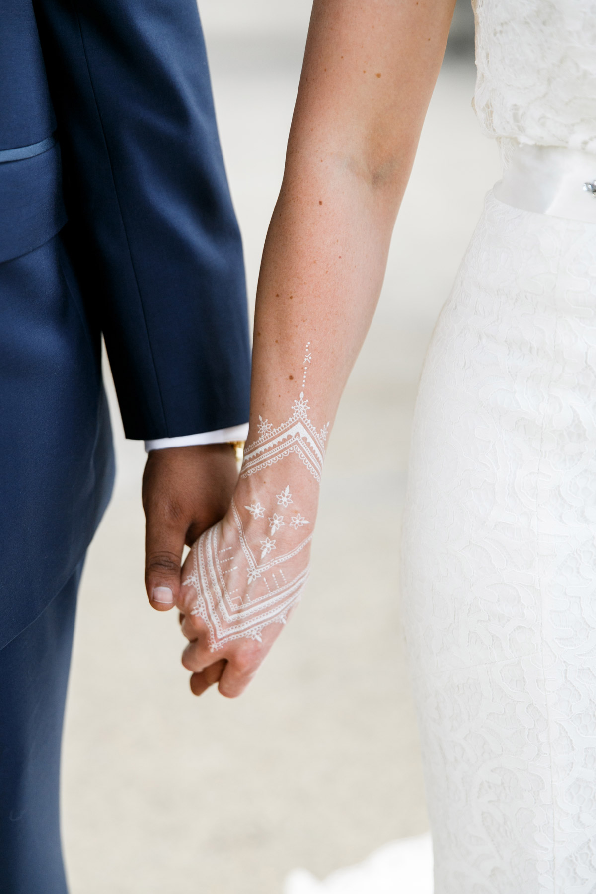 Detailaufnahme der Hände vom internationalen Brautpaar mit weißem Henna-Tattoo der Braut