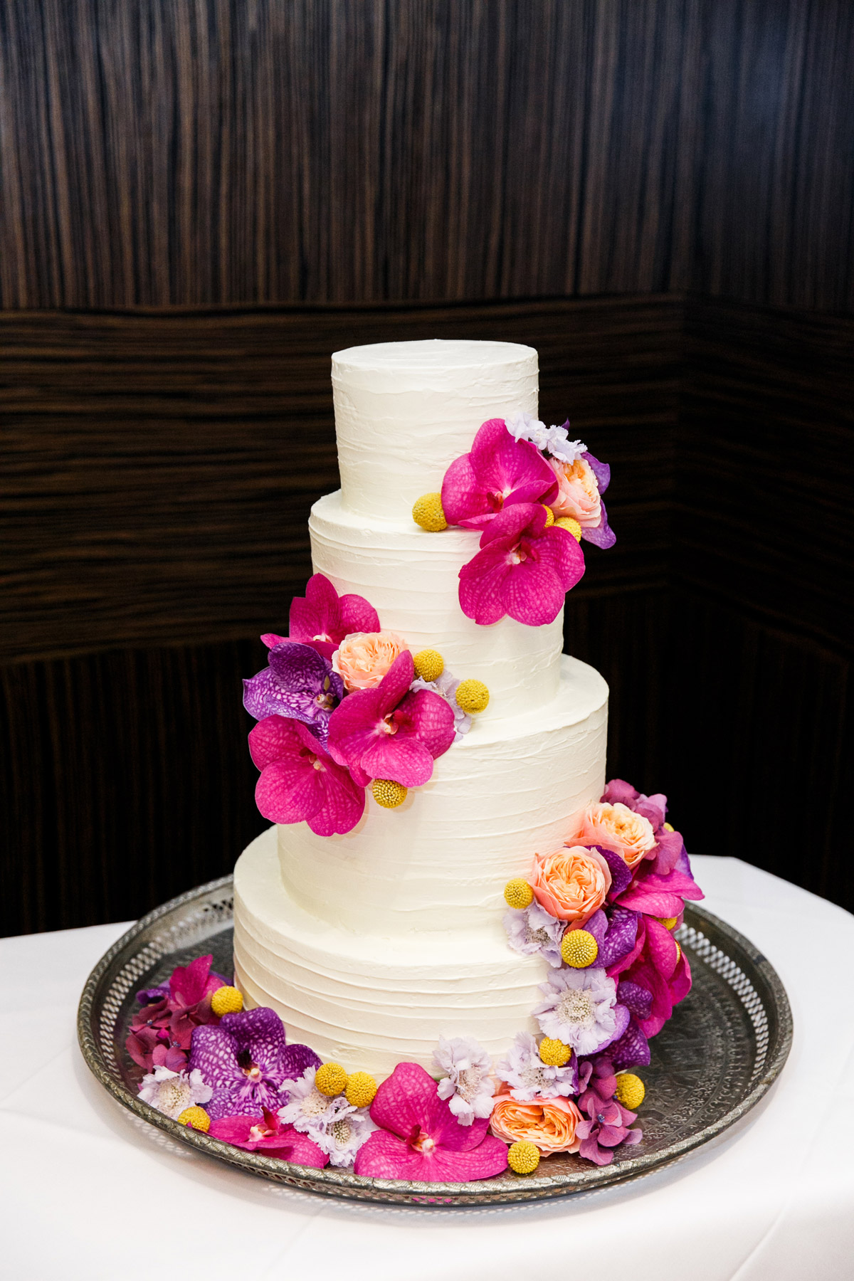 Vierstöckige Hochzeitstorte in Créme mit echten Blumen in Berlin: Elegantes Design mit vibrant pinken Orchideen und pfirsichfarbenen Rosen