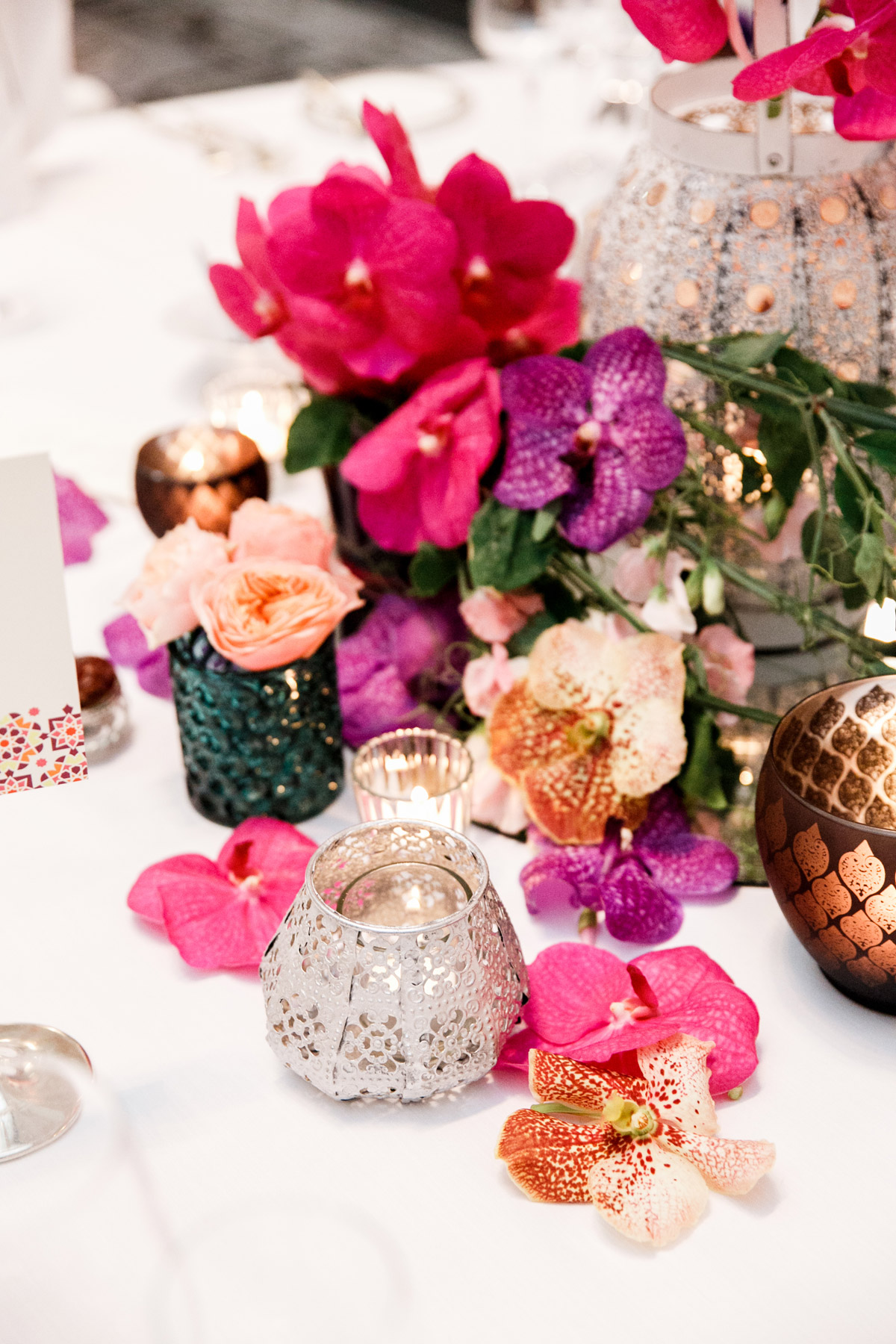 Farbenfrohe Hochzeitsfloristik von flores y amores Berlin: Detailaufnahme der Tischdeko mit magenta Orchideen, Rosen und orientalischen Windlichtern aus Silber