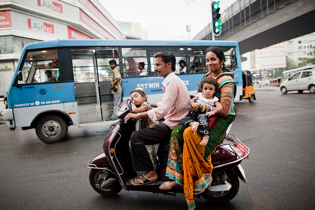 Hochzeitsreportage Indien: Authentische Street-Photography einer Familie auf dem Motorroller im lebhaften Straßenverkehr von Hyderabad