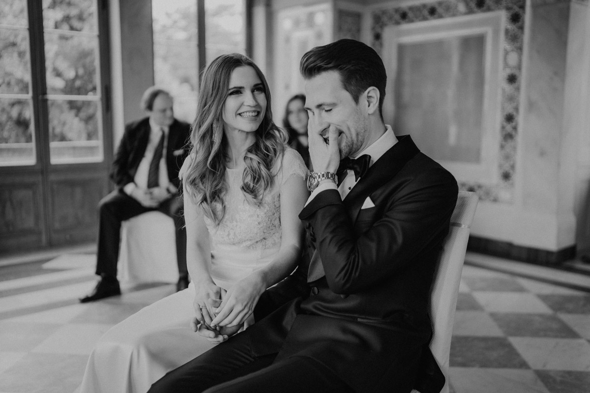 Echte Emotionen: Bräutigam wischt sich eine Träne weg, Braut lacht glücklich bei der Trauung