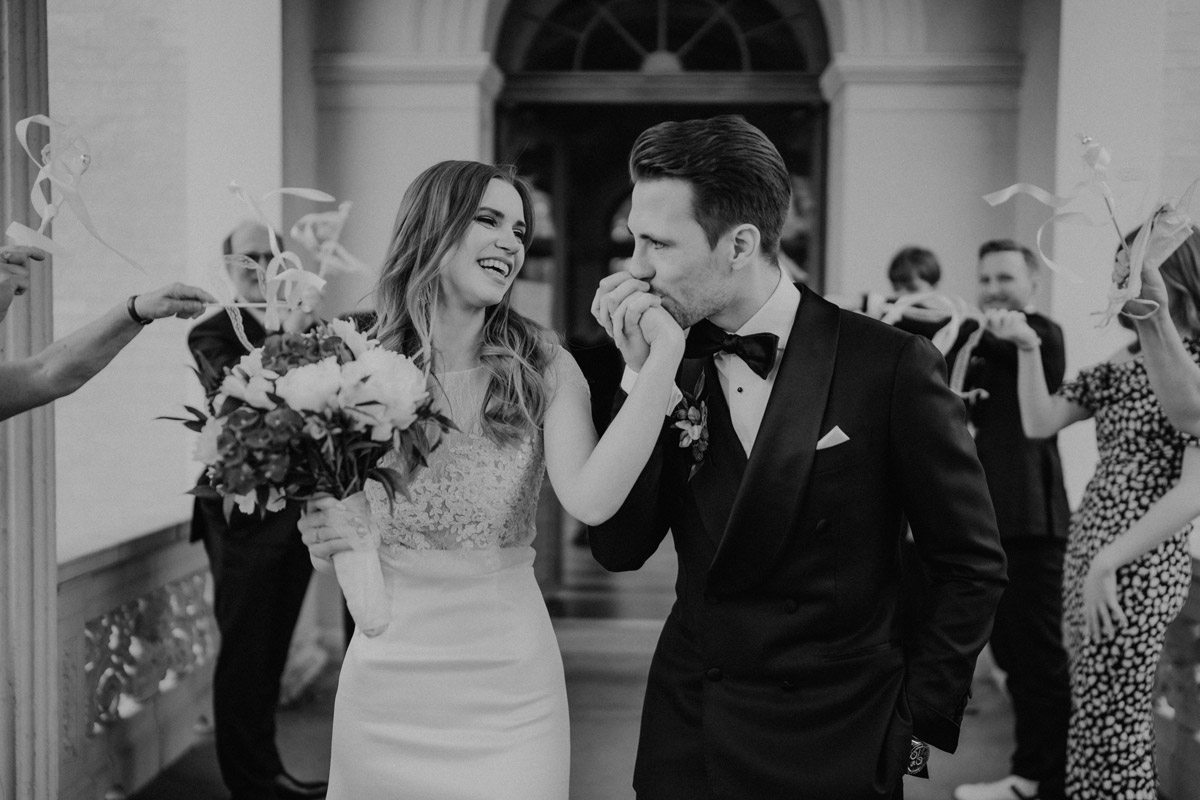 Romantischer Auszug: Bräutigam küsst der Braut die Hand – Schwarz-Weiß Aufnahme