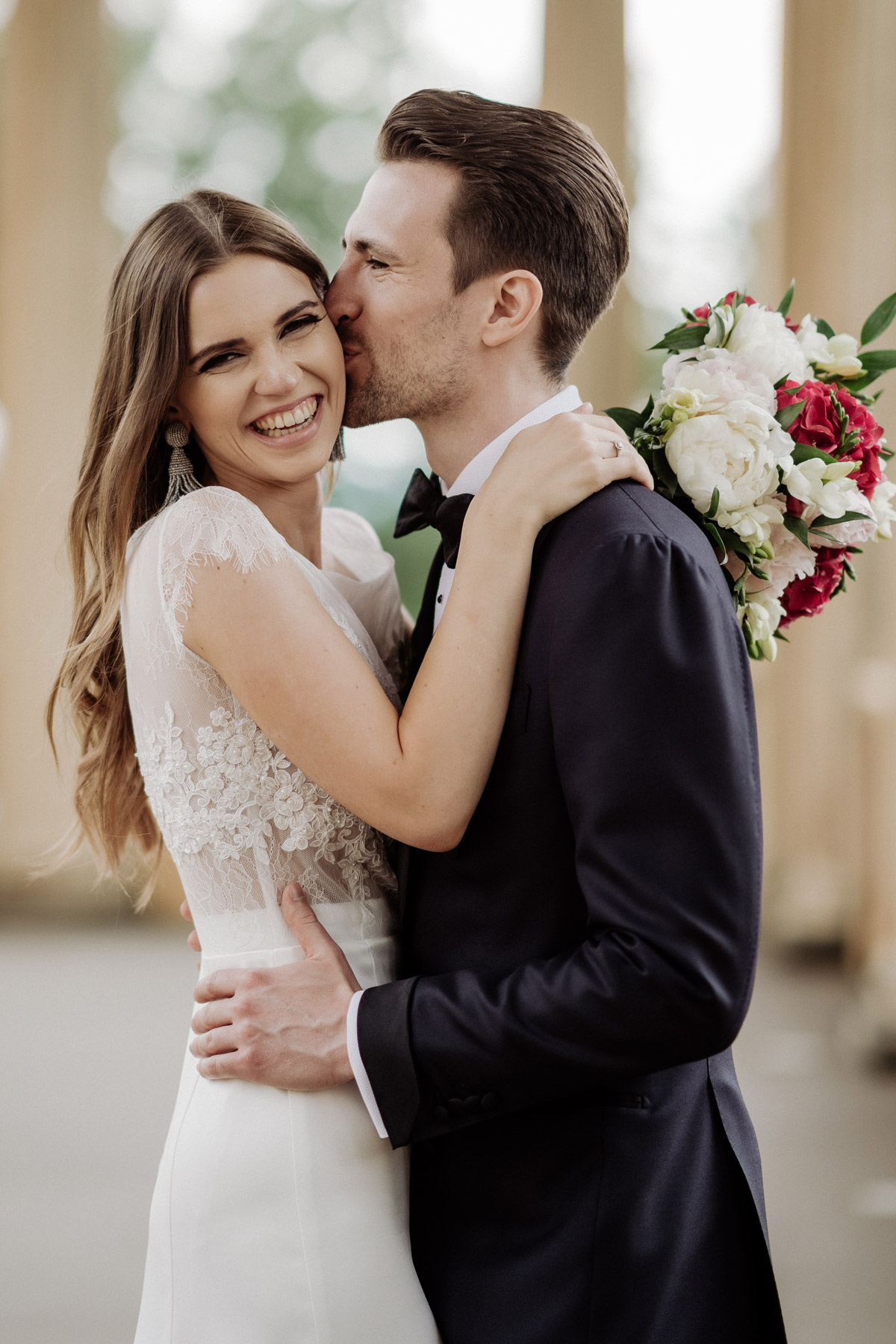 Brautpaarfotos Potsdam: Bräutigam küsst Braut auf die Wange, beide strahlen