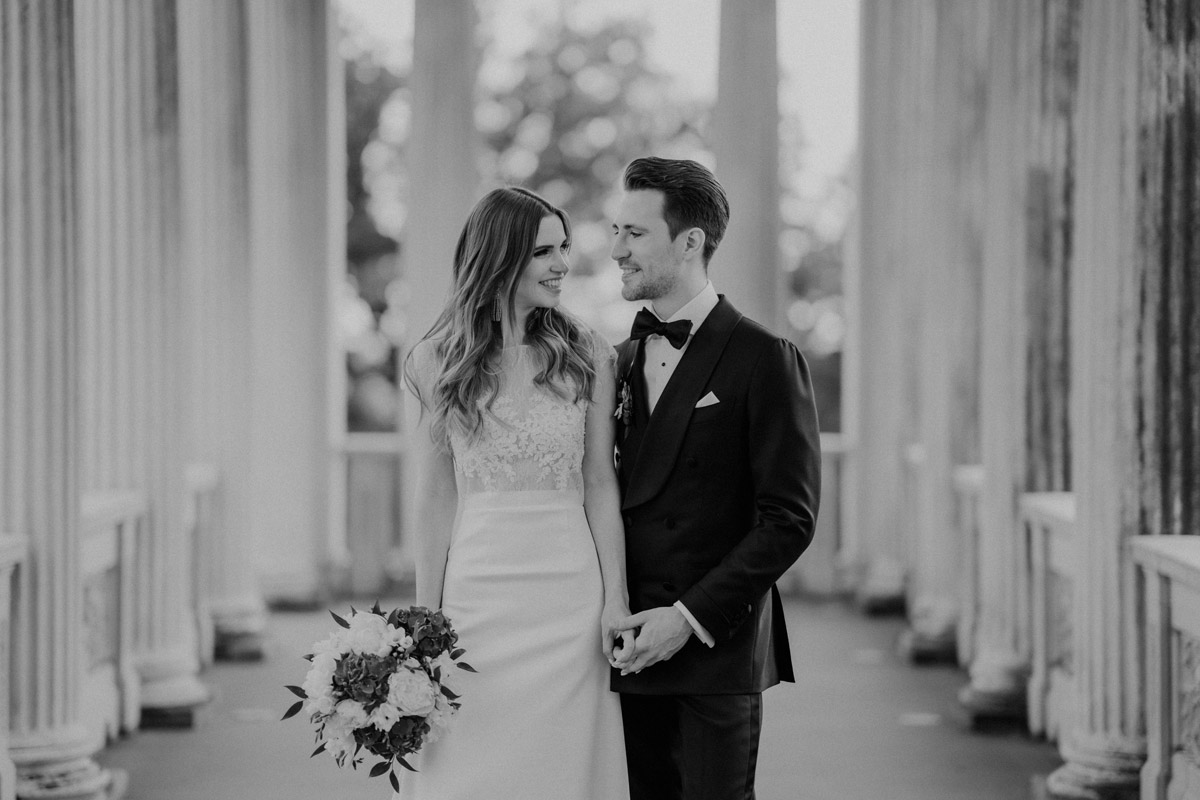 Klassisches Schwarz-Weiß Portrait: Braut und Bräutigam stehen Hand in Hand und schauen sich an