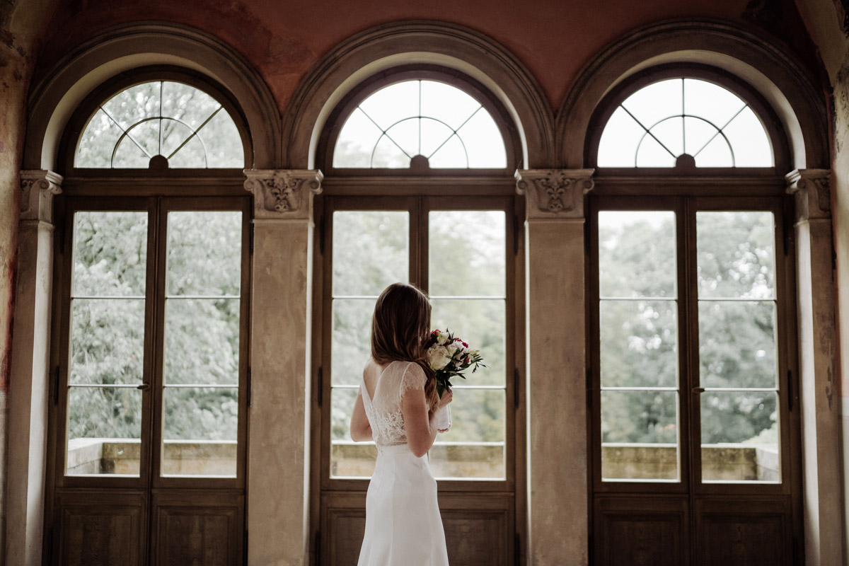 Brautkleid von hinten: Rückenansicht der Braut vor den Fenstern des Belvedere