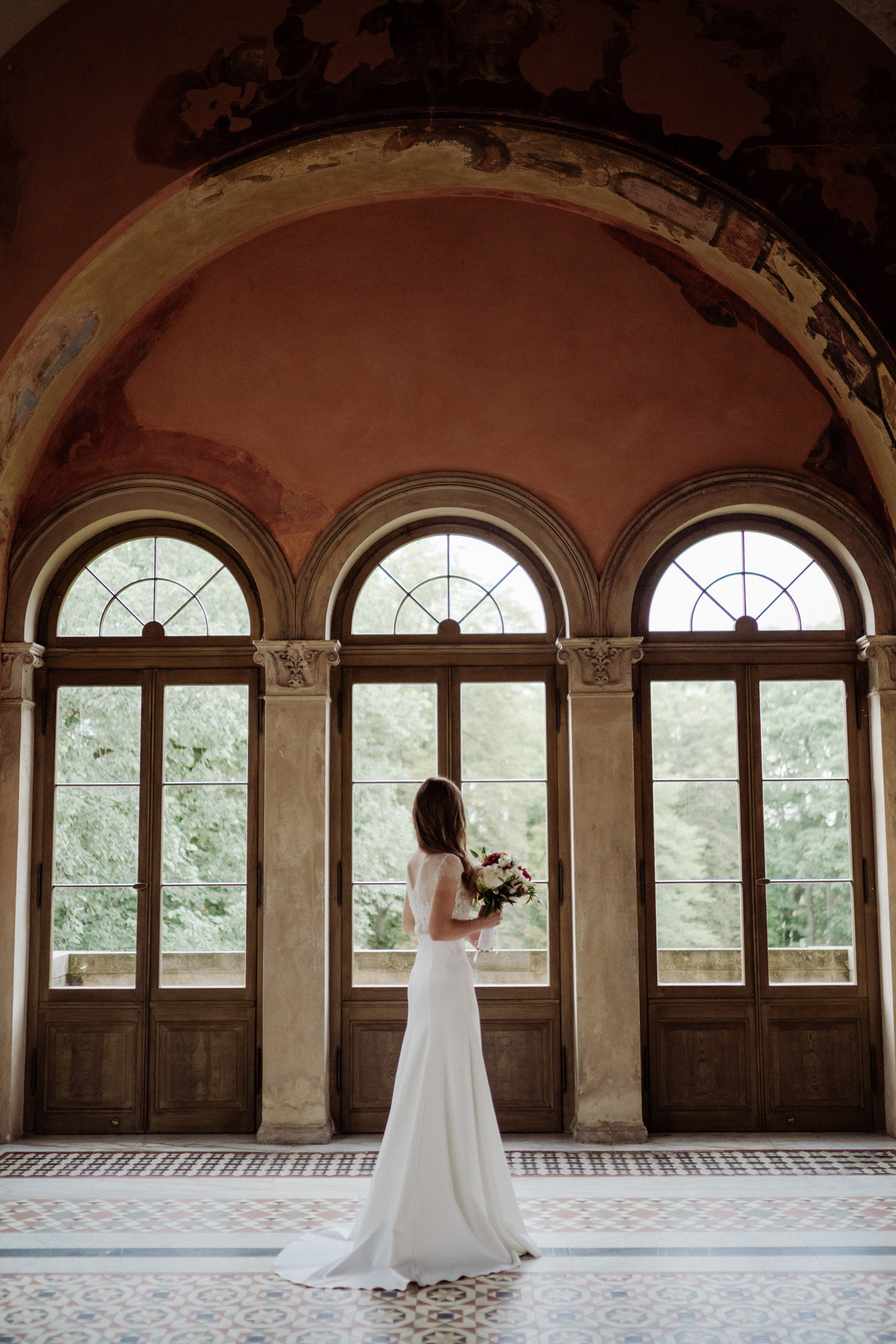 Silhouette der Braut vor den drei großen Rundbogenfenstern im Turm