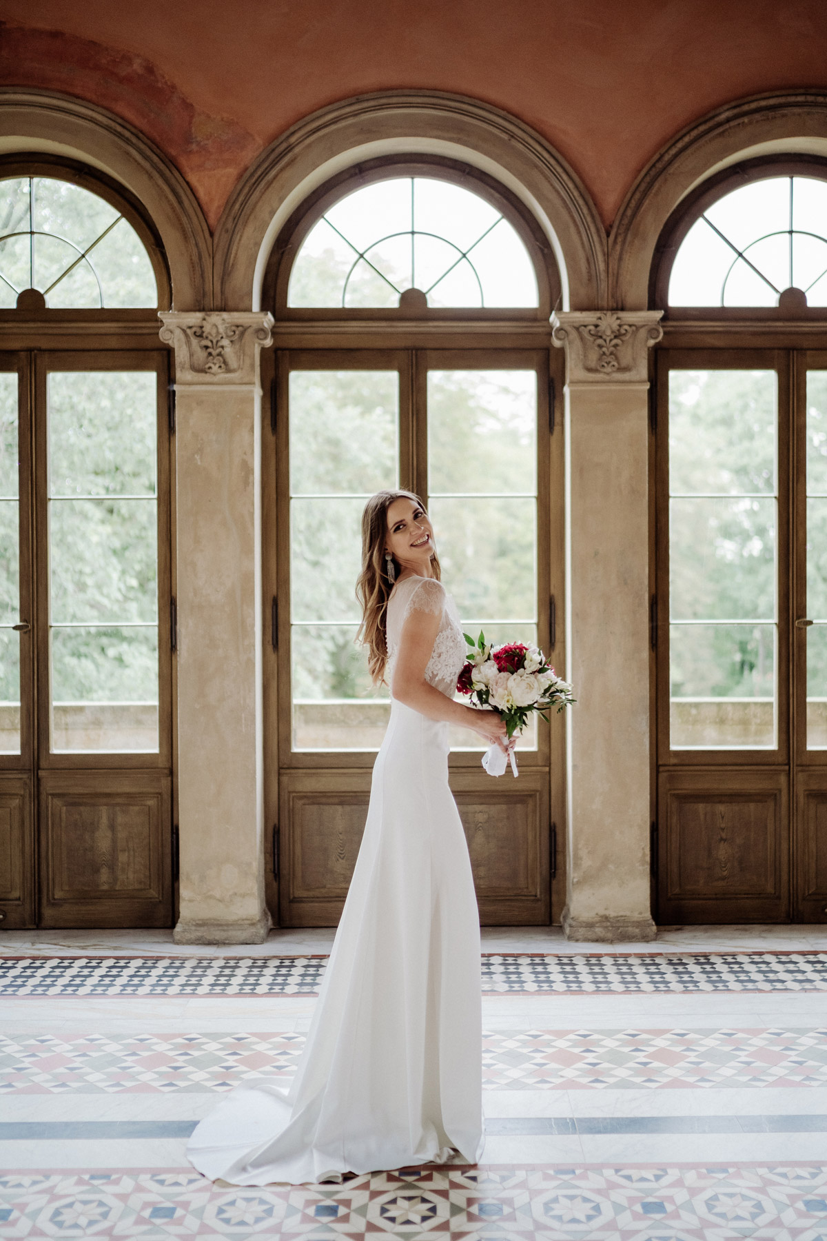 Brautportait: Lachender Blick über die Schulter in die Kamera der Hochzeitsfotografin aus Berlin