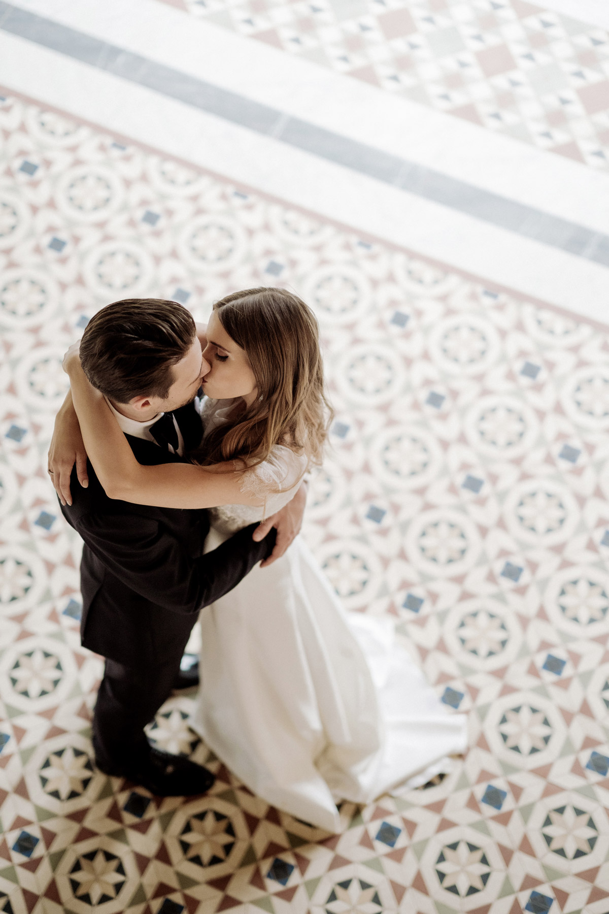 Kreative Perspektive: Kuss des Brautpaares von oben auf dem Mosaikboden im Maurischen Kabinett