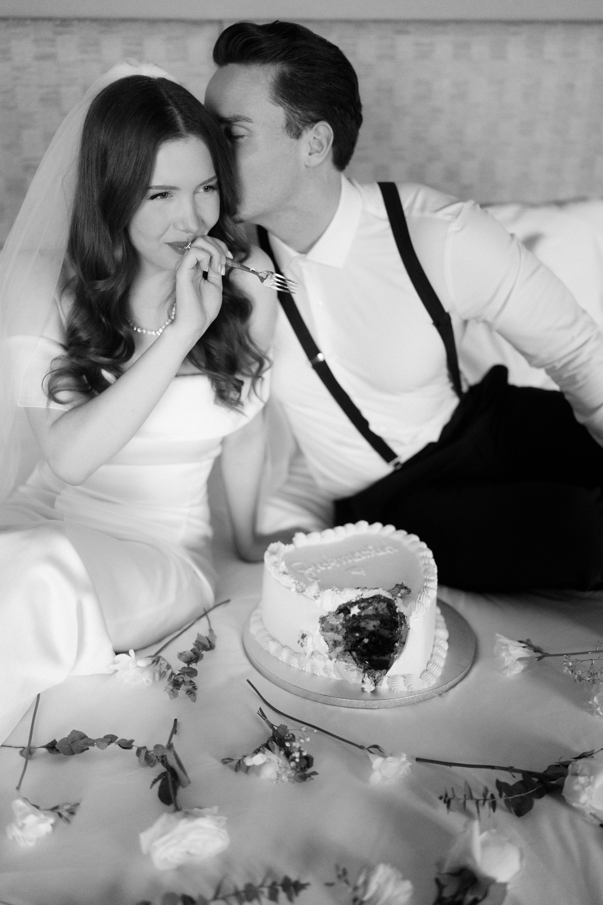 Urbanes Elopement im Hotel de Rome Berlin: Das Brautpaar genießt einen Statement Cake auf dem Bett der Hotelsuite. Ein authentischer Moment einer Hochzeit zu zweit in Berlin.