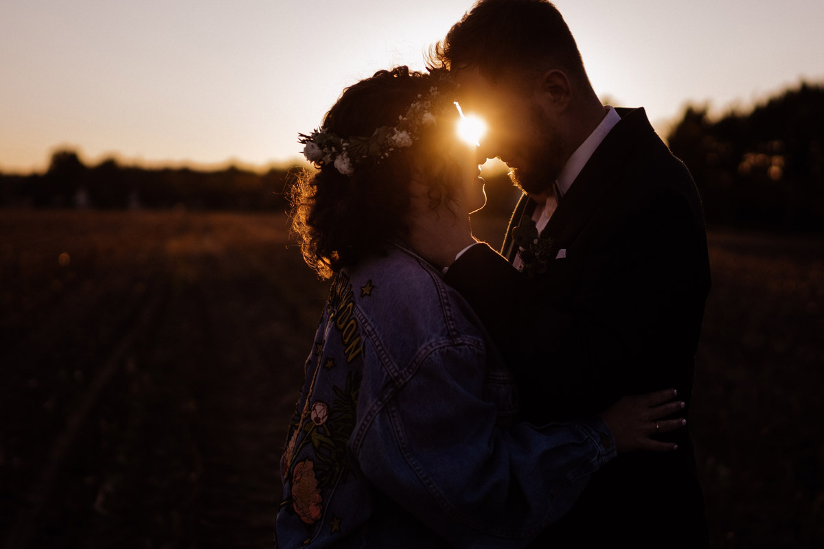 Romantische Silhouette eines Brautpaares auf einem Feld in Brandenburg bei Sonnenuntergang. Die Sonne strahlt zwischen den Köpfen hervor. Ein Beispiel für den Highlight-Film (Trailer) zum Online-Teilen mit euren Hochzeitsgästen.