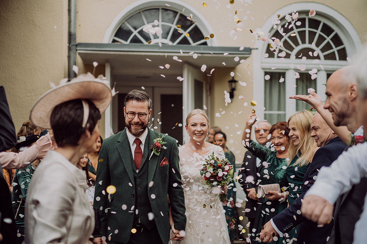 Fröhlicher Auszug des Brautpaares nach der standesamtlichen Trauung in Berlin mit buntem Konfetti-Regen der Gäste. Ein Beispiel für die lebendige Bildanzahl und die schnelle Lieferung eurer Hochzeitsgalerie.