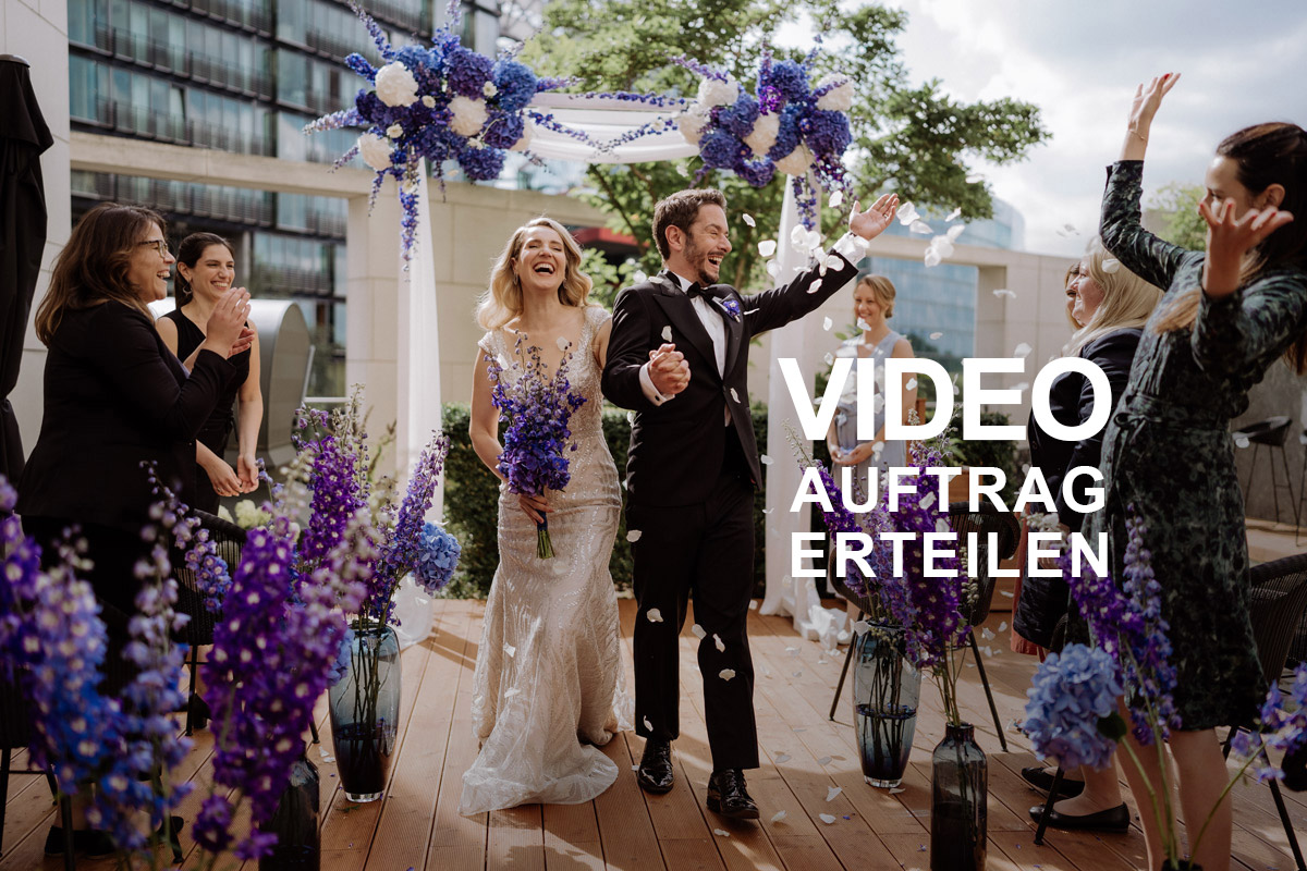 Strahlendes Brautpaar beim Auszug durch fliegendes Blüten-Konfetti. Klicke hier, um den Auftrag für dein Hochzeitsvideo in Berlin zu erteilen.