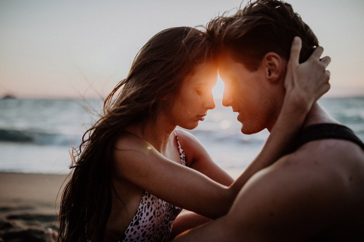 Romantisches Paarfoto am Meer: Die Köpfe liegen im warmen Gegenlicht des Sonnenuntergangs Stirn an Stirn. Tipps zur Buchung und Planung eures Shootings bei eurer Hochzeitsfotografin.