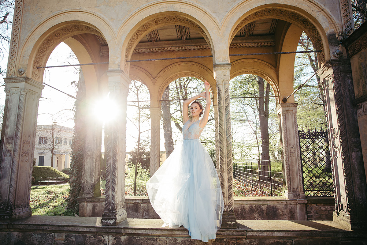 High-End Fashionpose einer Braut im hellblauen Kleid im Klosterhof von Schloss Glienicke. Ein Beispiel für die aufwendige Produktion und den Wert des Rohmaterials bei einem Hochzeitsvideo in Berlin und Potsdam.