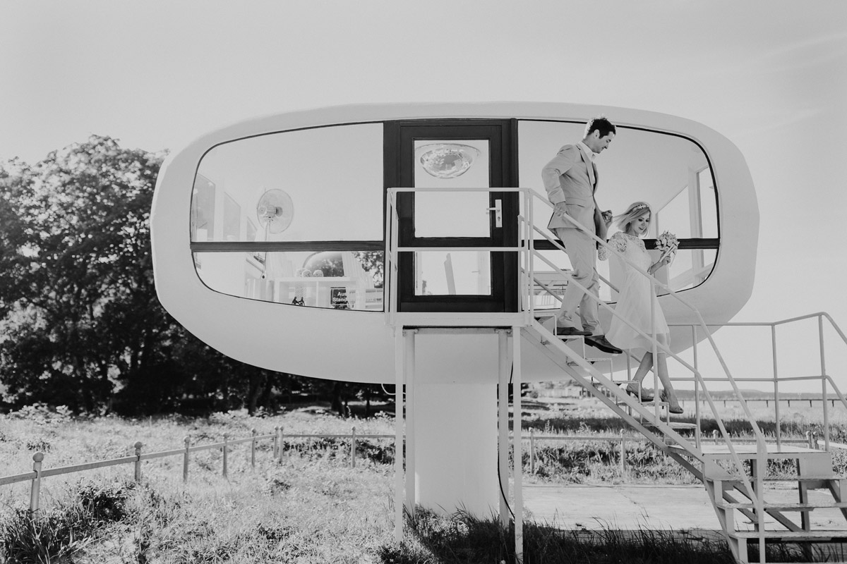 Brautpaar läuft nach der standesamtlichen Trauung im Rettungsturm Binz die Außentreppe hinunter. Inspiration für die Dauer der fotografischen Begleitung beim Standesamt von Hochzeitsfotografin Berlin.